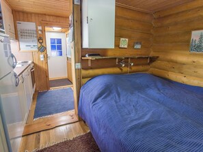 A compact cabin with a bed, a small kitchenette, and a door leading to an outdoor area. - Vacation home  by Interhome (Äkäslompolo)