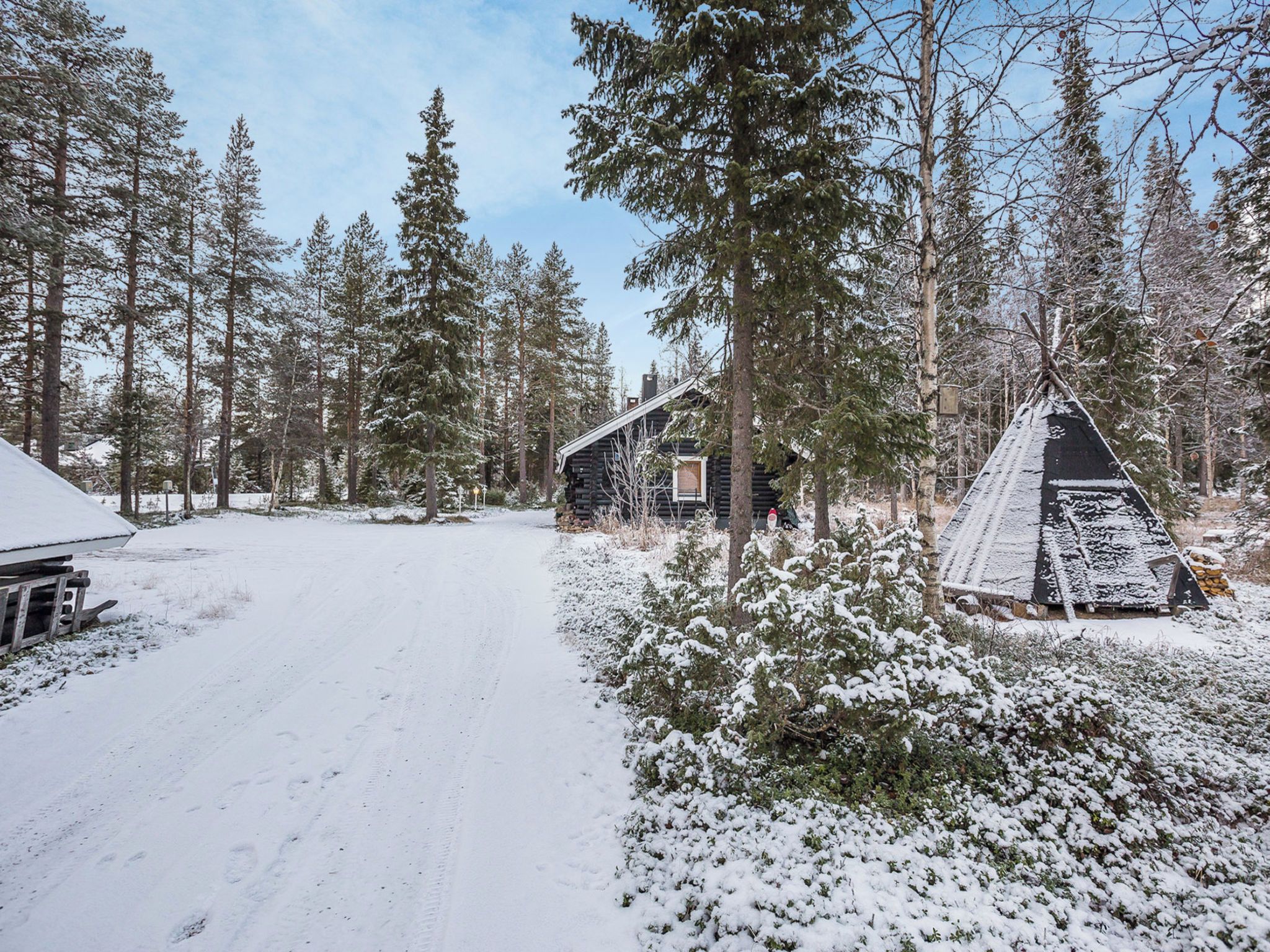 En snötäckt skog med en stuga och ett tipi-tält.