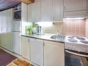 A kitchen with white cabinets, a built-in oven, a coffee maker, and a sink. - Vacation home  by Interhome (Äkäslompolo)