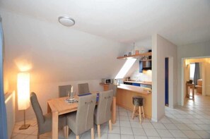 Eine kleine Küche mit Essbereich, einem Hocker und einem Tisch mit Stühlen.