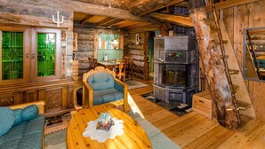 L’intérieur d’un chalet rustique en rondins de bois comprend un coin repas, une cheminée et un escalier.
