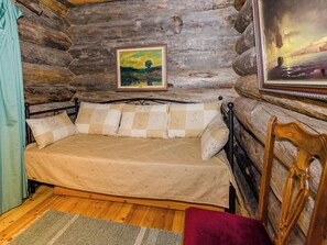 A log cabin bedroom with a bed, pillows, a framed painting, and a wooden headboard. - Köllölä 2 by Interhome (Nunnanlahti)