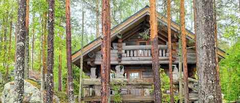 Una cabana de fusta envoltada d'alzines altes en un bosc.