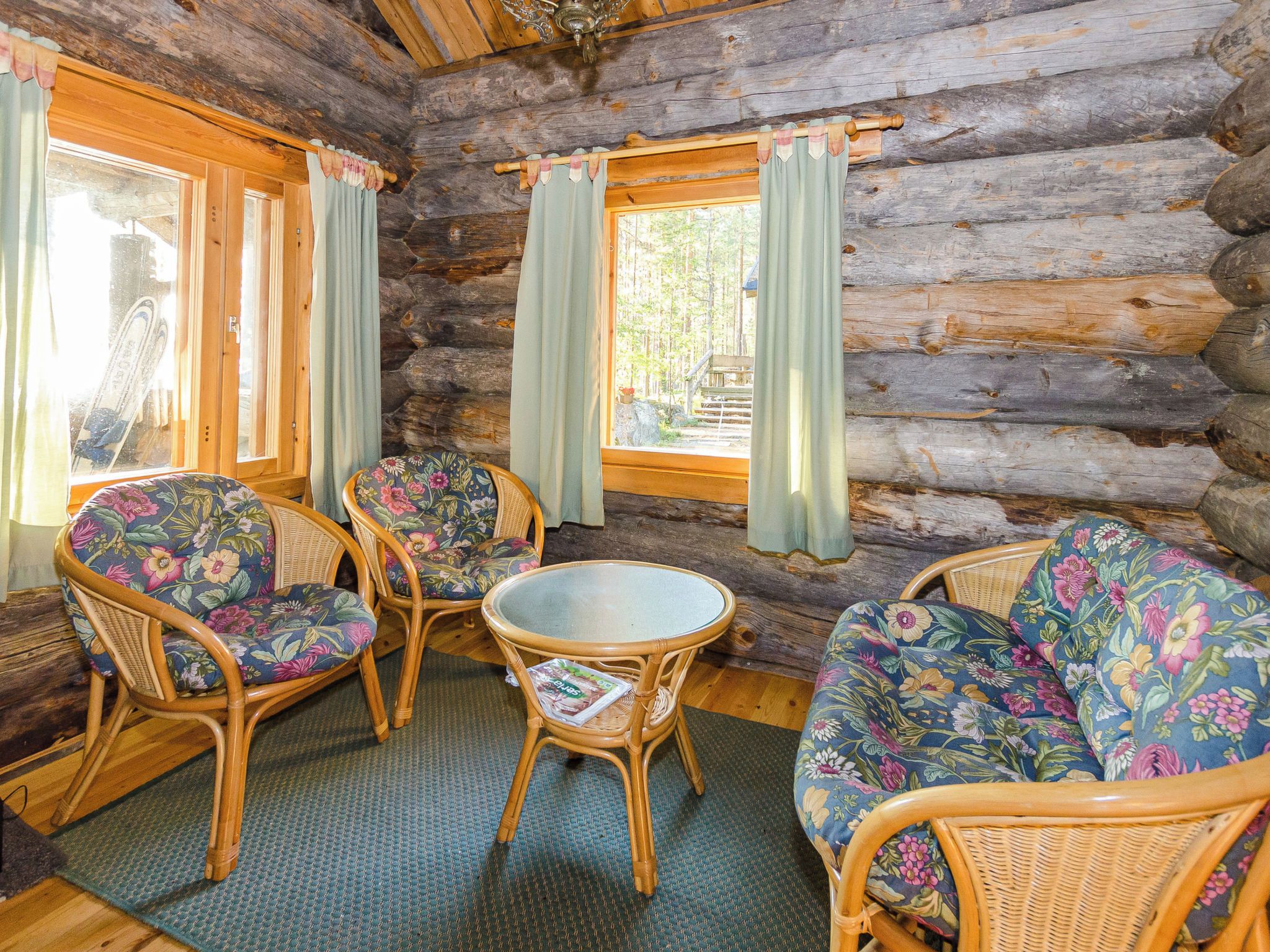 A log cabin interior with wicker furniture and a glass-top table.