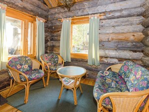 A log cabin interior with wicker furniture and a glass-top table. - Köllölä 2 by Interhome (Nunnanlahti)