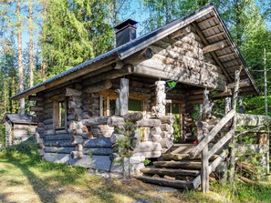 Eine rustikale Blockhütte mit einer steilen Treppe zum Eingang, umgeben von einem Wald.