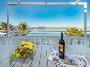 Une table avec une bouteille de vin, un panier de fruits et un set de table orné de motifs floraux.