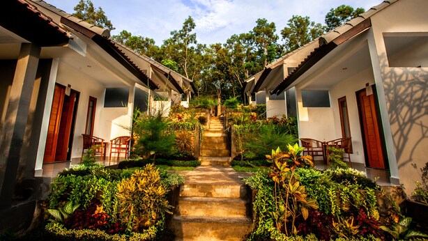 A traditional building with a central staircase surrounded by lush greenery. - Singgahan Bungalow by ecommerceloka (Penida Island)