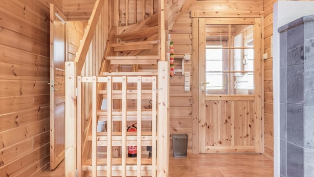 Interior de madera con una escalera, una puerta con paneles de vidrio y una pared de azulejos.