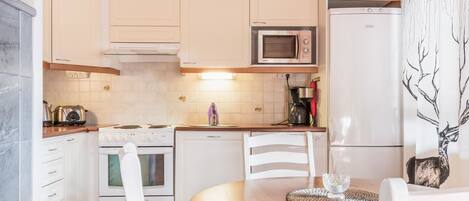 Een koelkast, een magnetron, een vaatwasser, kookgerei, borden en bestek