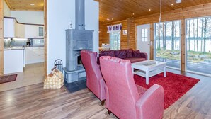 Interior acogedor de una cabaña con estufa de leña, un sofá y una zona de comedor.