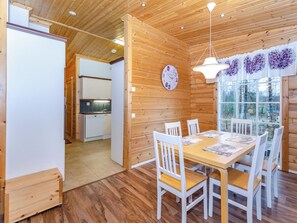 A wooden interior with a dining table, chairs, a clock, and a window with a view of trees. - Kolin mesikämmen by Interhome (Lieksa)