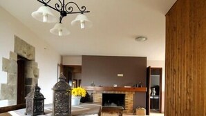 A dining area with a wooden table, a chandelier, and a fireplace. - Rural house (full rental) Masia Pallares de Dalt for 10 people (Olius)