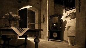 A dimly lit room with a wooden table, a bench, and a small cabinet. - Rural house (full rental) Masia Pallares de Dalt for 10 people (Olius)