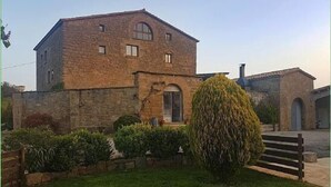A stone building with a rectangular shape, a central arched window, and a small balcony. - Rural house (full rental) Masia Pallares de Dalt for 10 people (Olius)