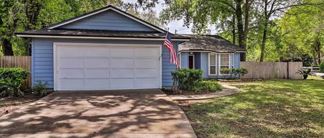 A residential house with a garage, a small porch, and a well-maintained lawn.