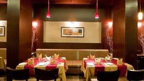 A restaurant with booths and tables set for dining, featuring red and white checkered tablecloths, and pendant lighting. - Hotel Imperial (Ujjain)
