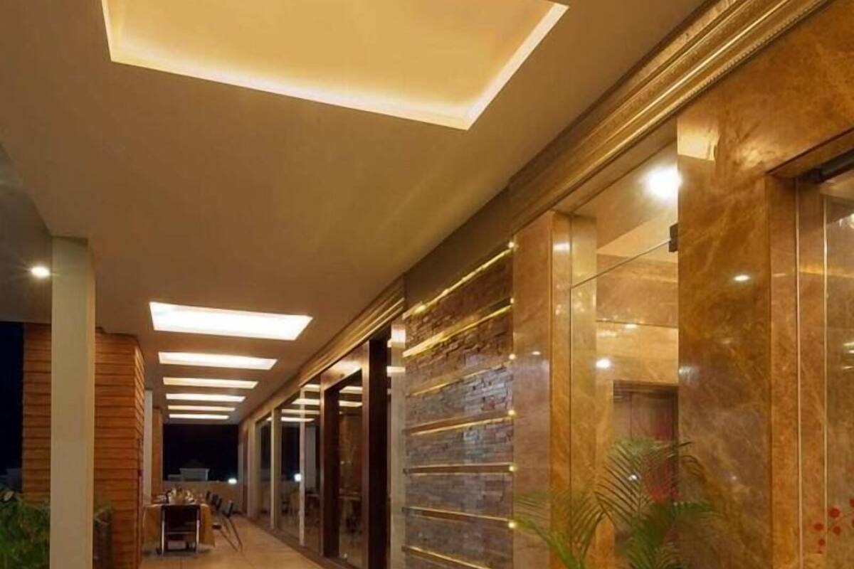 A corridor with a tiled floor, a potted plant, and a wall with a textured pattern.