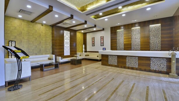 A modern reception area with a reception desk, seating area, and decorative wall panels. - Hotel Imperial (Ujjain)