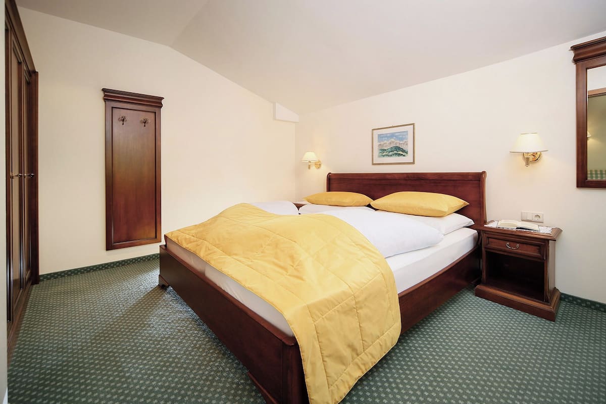 Une chambre d’hôtel avec un grand lit, une table de chevet, une armoire en bois et un tableau au mur.