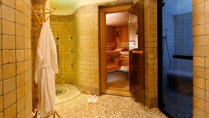 Una sala de sauna con un banco de madera, un perchero y una zona de ducha con suelo de baldosas.