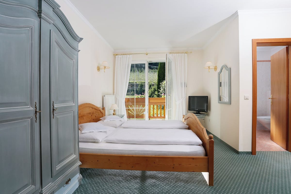 Une chambre à coucher avec un lit, une télévision, un miroir et une vue sur l’extérieur.