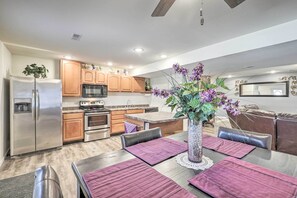 A modern kitchen with wooden cabinets, stainless steel appliances, and a dining area with purple placemats.