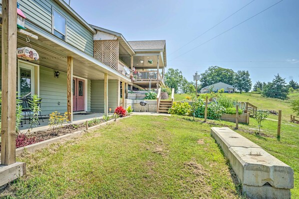 A two-story house with a front porch, a covered patio, and a small garden area.