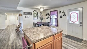 A kitchen with granite countertops, wooden cabinets, and a dining area with a table and chairs. - Kimberly's Hope Clark Apt on Farm w/ Pool Access (Clark)