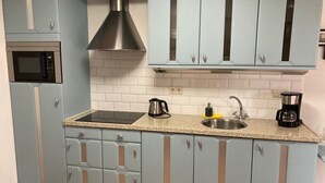 A kitchen with light blue cabinets, a stainless steel range hood, a microwave, a sink, and a coffee maker. - Peace & Space in a real Wieringer residential farmhouse. (Westerland)