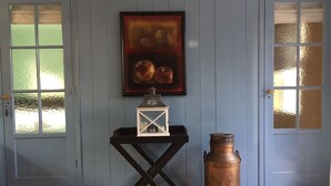 A room with a blue door, a framed painting of fruits, a white lantern, and a copper pot on the floor. - Peace & Space in a real Wieringer residential farmhouse. (Westerland)