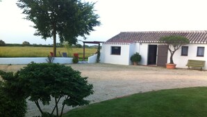 A white building with a tiled roof, a gravel driveway, and a grassy lawn.