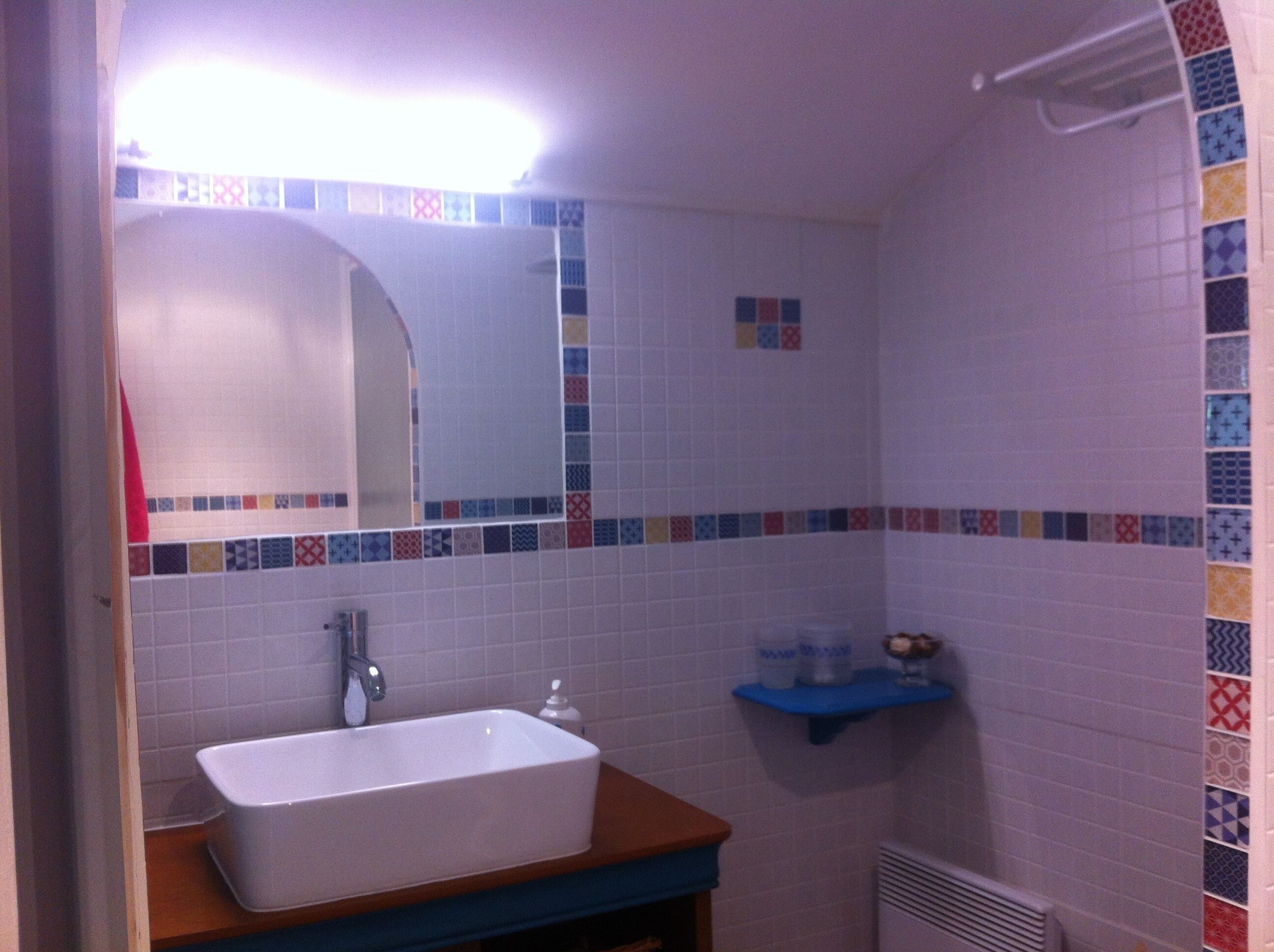 Une salle de bain avec un lavabo rectangulaire, un miroir et un espace douche.