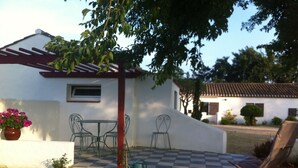 A small white building with a red roof, a checkered patio, and a red chair.