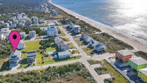 Vista aerea di una zona residenziale sulla costa, con case, spiaggia e un molo.