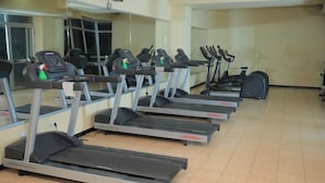 A row of treadmills in a gym with mirrored walls and a tiled floor. - Debredamo hotel (Addis Ababa)