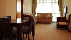 A living room with a dining table, chairs, a sofa, and a TV. - Debredamo hotel (Addis Ababa)