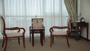 A room with two wooden chairs, a small table with a vase of flowers, and a radiator. - Debredamo hotel (Addis Ababa)