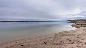 A calm beach with clear water and rocky terrain. - 2-Level Home w/ Deck: 1/2 Mi to Lake McConaughy! (Lemoyne)