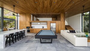 Een moderne keuken met een pooltafel, bar en een zithoek met een bank en salontafel.