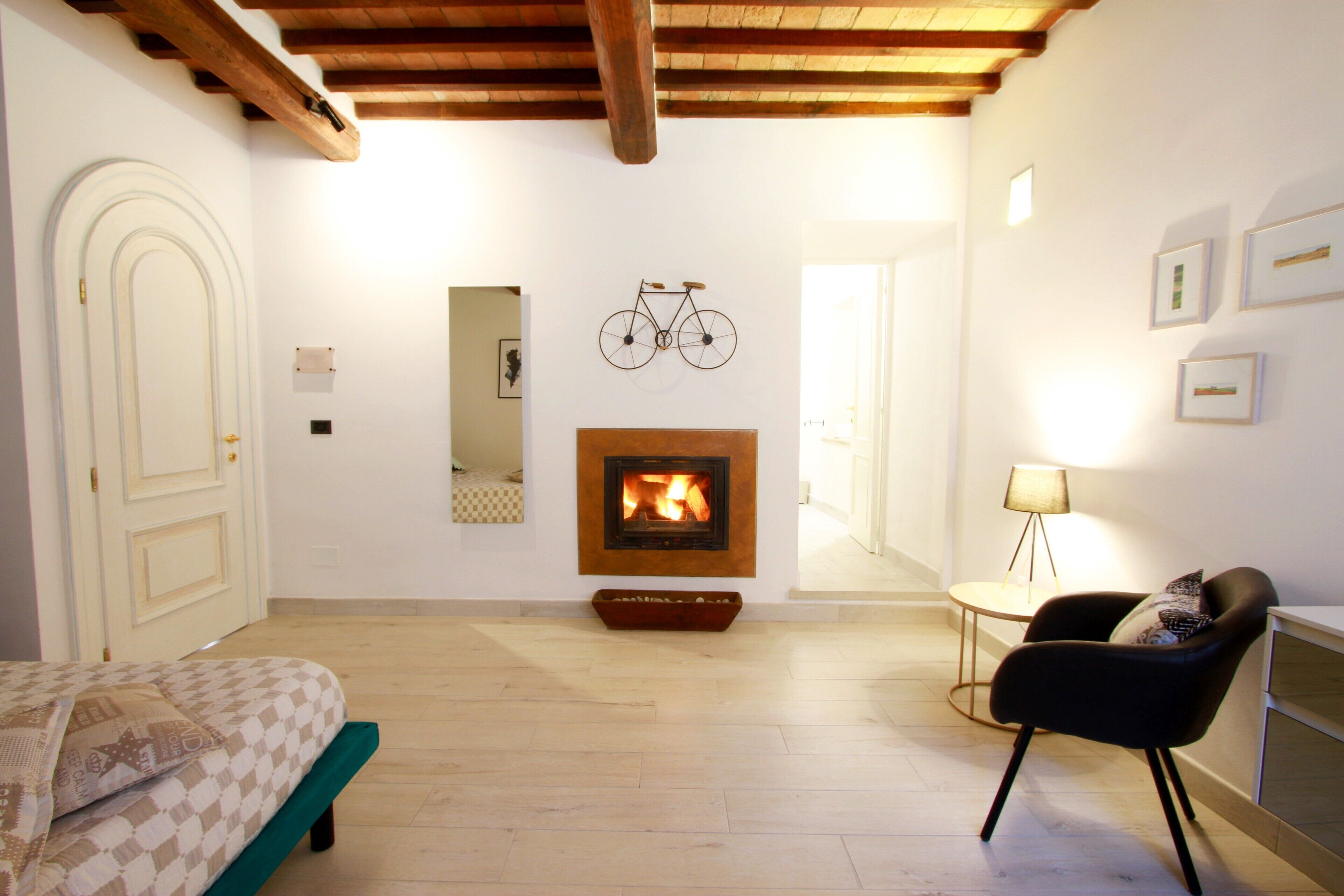 Une pièce avec une cheminée, un lit, une chaise et une décoration murale représentant un vélo.