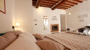 A bedroom with a large bed, a wooden ceiling, a mirror, a bicycle, and a chair. - "Il Focolare" Superior Apartment in Monticchiello (Monticchiello)
