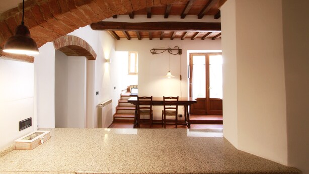A kitchen with a granite countertop, a hanging pendant light, and a brick archway. - "Il Focolare" Superior Apartment in Monticchiello (Monticchiello)