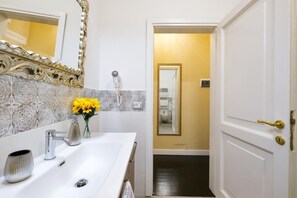 A bathroom with a white sink, a mirror with an ornate frame, and a door leading to a hallway. - B&B Kingsman (Florence)