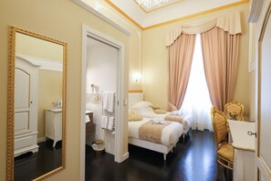 A hotel room with two beds, a vanity with a mirror, a chest of drawers, and a chandelier. - B&B Kingsman (Florence)
