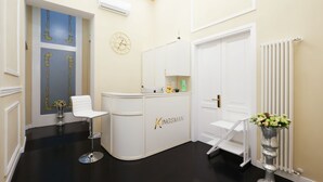 A reception area with a white counter, a clock, and a radiator. - B&B Kingsman (Florence)