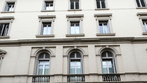 A building with a large wooden door, multiple windows, and a stone facade. - B&B Kingsman (Florence)