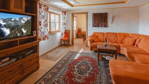 A living room with a large flat-screen TV, a sofa, a coffee table, and a patterned rug. - Lena Top 2 by Interhome (Königsleiten)