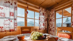 A wooden dining table with a bowl of fruit, plates, and cutlery. - Lena Top 2 by Interhome (Königsleiten)