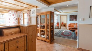 A spacious room with wooden ceiling beams, a large cabinet with glass doors, and a view into a living area with a sofa and rug. - Lena Top 2 by Interhome (Königsleiten)